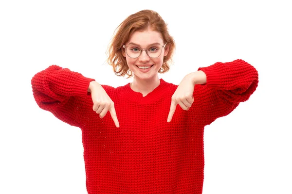 穿着红色圣诞毛衣的形象积极的红头发女青年微笑着用手指指指空白对照的文字或产品 做广告横幅 — 图库照片