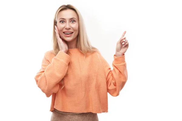 Joyful Blonde Girl Orange Casual Smiling Points Finger Empty Copy — Stock Photo, Image