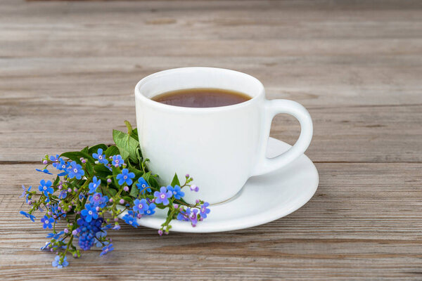 Happy mother's day greeting card; white cup of coffee or tea and bouquet of blue forget-me-not flowers