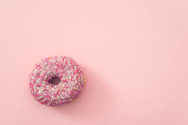 Pink background with one decorated doughnut; space for text