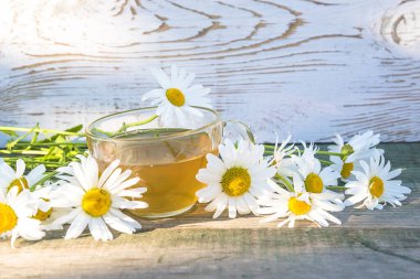 Cam fincanda çay ve kırsal ahşap arka planda beyaz papatya çayı.