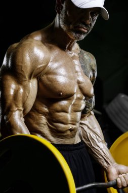 Vahşi ve kaslı güçlü vücut geliştirme sporcusu spor salonunda kaslarını şişiriyor. Spor ve sağlık geçmişi