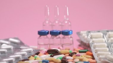 Money falls on olored drugs tablets, pills, ampoules, falling down on pink background. Pharmacy medicine and health care concept