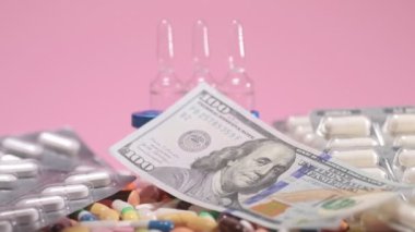 Money falls on olored drugs tablets, pills, ampoules, falling down on pink background. Pharmacy medicine and health care concept