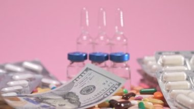 Money falls on olored drugs tablets, pills, ampoules, falling down on pink background. Pharmacy medicine and health care concept