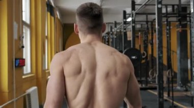 Kaslı atletik adam spor salonunda yürüyor. Arkadan bak. Yüzü yok. Spor, ağırlık kaldırma ve sağlık hizmetleri kavramı 