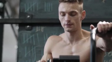 Kaslı atletik adam spor salonunda sabit kardiyo bisiklet egzersizi yapıyor. Spor ve kardiyo sağlık konsepti