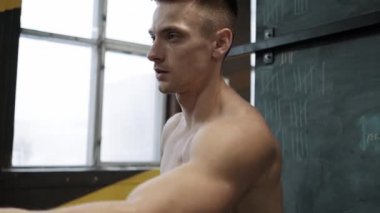 Kaslı atletik adam spor salonunda sabit kardiyo bisiklet egzersizi yapıyor. Spor ve kardiyo sağlık konsepti