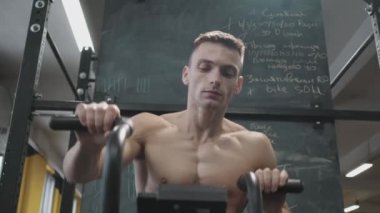 Kaslı atletik adam spor salonunda sabit kardiyo bisiklet egzersizi yapıyor. Spor ve kardiyo sağlık konsepti