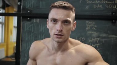 Kaslı atletik adam spor salonunda sabit kardiyo bisiklet egzersizi yapıyor. Spor ve kardiyo sağlık konsepti