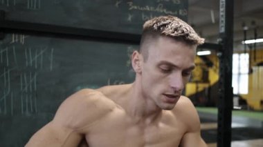 Kaslı atletik adam spor salonunda sabit kardiyo bisiklet egzersizi yapıyor. Spor ve kardiyo sağlık konsepti