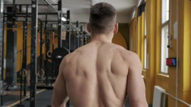 Kaslı atletik adam spor salonunda yürüyor. Arkadan bak. Yüzü yok. Spor, ağırlık kaldırma ve sağlık hizmetleri kavramı 