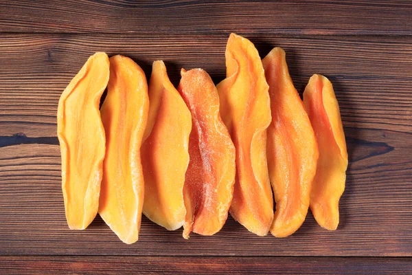 Ahşap zemin üzerinde kurumuş mango dilimlerinin üst görünümü.