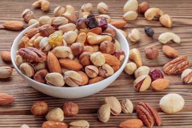 View of mixed nuts on wooden background. Walnut, pistachios, almonds, hazelnuts and cashews. Soft focus.