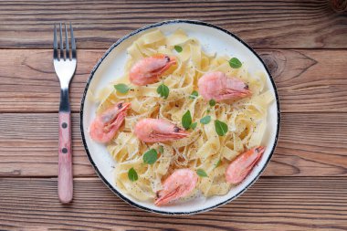 Karidesli makarna ve kırsal tabakta ahşap arka planda çatal..