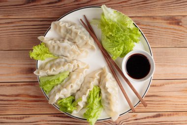 Soya soslu haşlanmış Çin hamur köftesi ve ahşap arka planda yeşil salata..