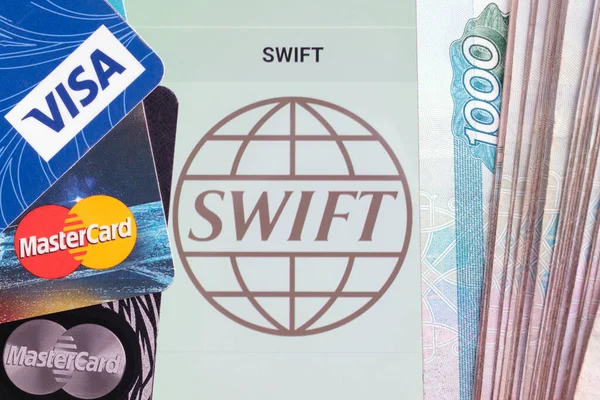 Moskova, Rusya - 28 Şubat 2022: Visa ve Mastercard logoları ve Rus banknotları 1000 ruble ve SWIFT logosu olan banka kartlarının üst görüntüsü. Yaptırım kavramı.