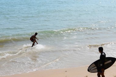 Aonang, Krabi, Tayland 'da bir plajda dalga yakalayan kaykaylı iki adam, sol tarafa odaklan.