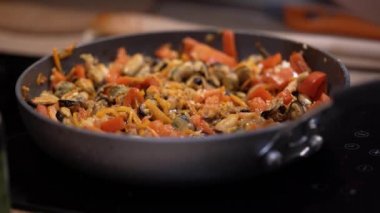 Elleri kızartma tavasına sosu deniz ürünleri ve sebzelerle doldurdu..