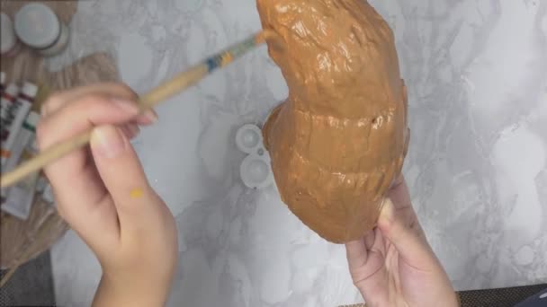Kvinnors händer måla vitt horn med brun färg. — Stockvideo