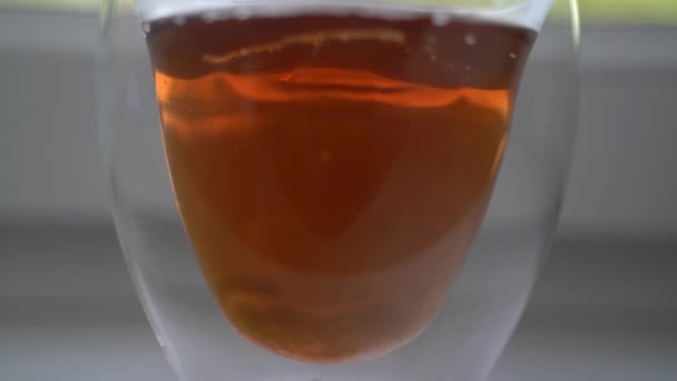 Dans une tasse de thé parfumé debout sur le rebord de la fenêtre, verser quelques cuillères de sucre. — Video