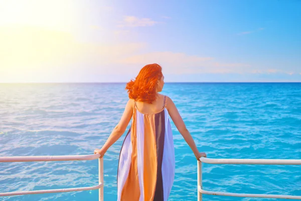 Schattig meisje in vloeiende lange jurk staat op de rand van de zee pier. — Stockfoto