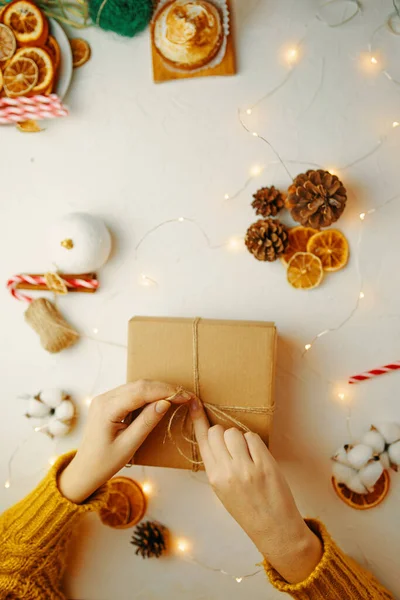 Frau bindet Schleife an Weihnachtsgeschenk. — Stockfoto