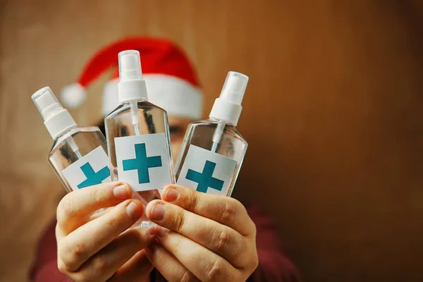Sanitizers with turquoise cross on label in hands. — Stock Photo, Image