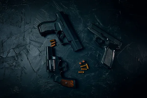 Three guns and bullets on black table. — Stock Photo, Image