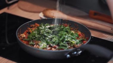 Susam baharatları tavaya dökülür ve ahşap kaşıkla karıştırılır..