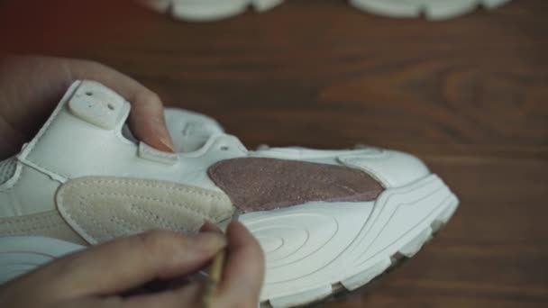 Kvinnlig konstnär målar vita sneakers på träbord. — Stockvideo