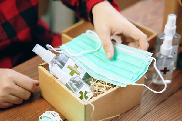 Mens hands put medical masks in a gift box with alcohol antisep — Stock Photo, Image