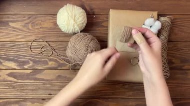 Kadınların elleri kumral ipliği karton parçasına sürer..