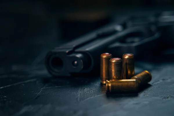 Pistola con cartuchos sobre mesa de hormigón oscuro. — Foto de Stock