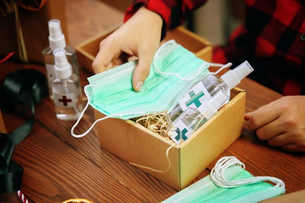 Hände von Menschen sammeln Geschenke während der Quarantäne in einer Schachtel. — Stockfoto