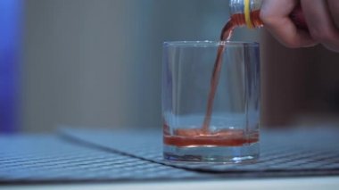 Kadın elleri bardağa soda döker ve masadan kaldırır..