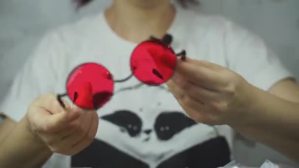 Frauenhände zeigen farbige Brillen mit roten Gläsern. — Stockvideo
