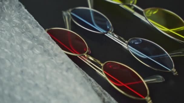 Disimballaggio di occhiali colorati su tavolo nero. — Video Stock