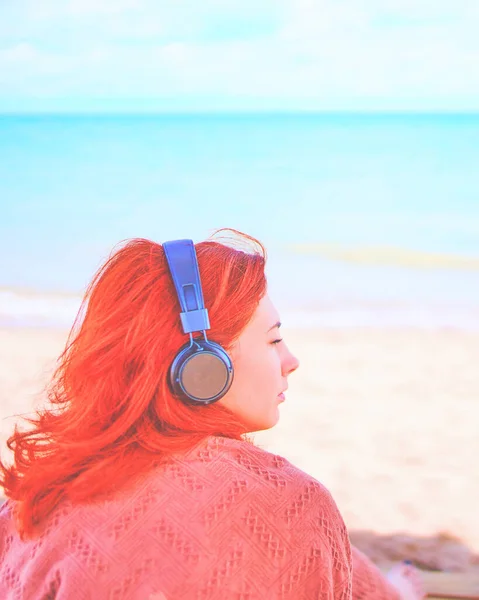 Schöne Frau hört Musik am Strand. — Stockfoto