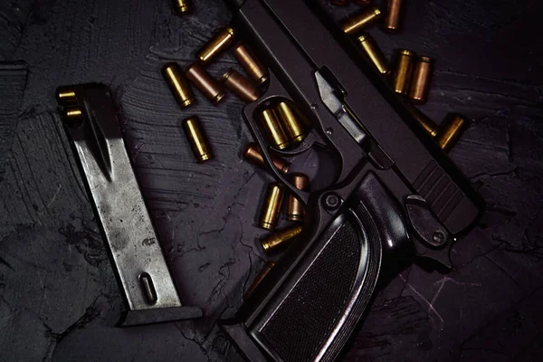 Pistole s náboji na černém betonovém stole. — Stock fotografie