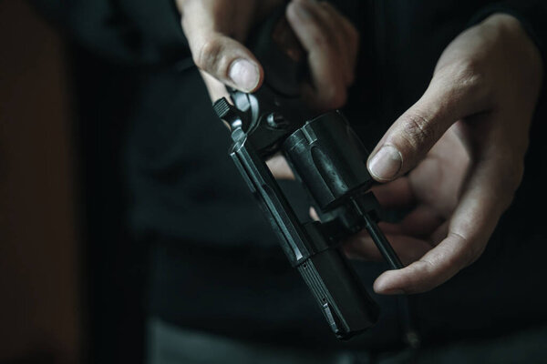 Mens hands check for bullets in revolver barrel.