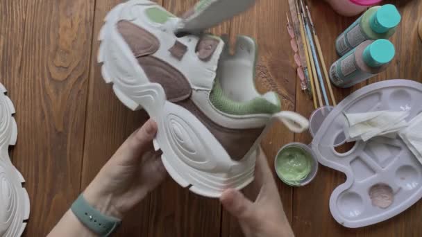 Womens hands take colored sneaker and twist it in front of camera. — 图库视频影像