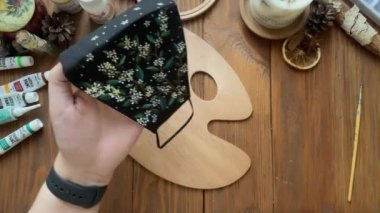 Kadınların elleri, tıbbi giysi maskesine fırçayla çiçek çizer..