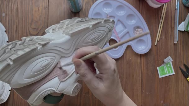 Females hands dip brush in brown paint and apply it to sneaker. — Stock Video
