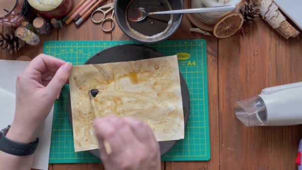 Жінка прикрашає ремісничий папір у тарілці з водою та кавою . — стокове відео
