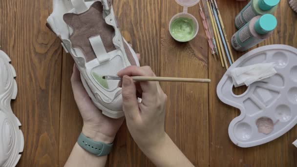 Womens hands paint white boots with brush on desktop. — 图库视频影像