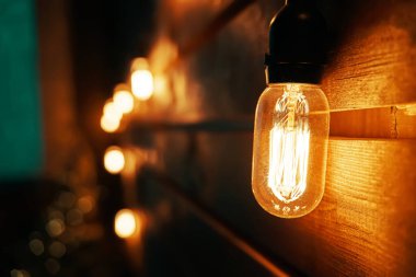 Antik parlak Edison tipi ampuller ahşap duvarda.