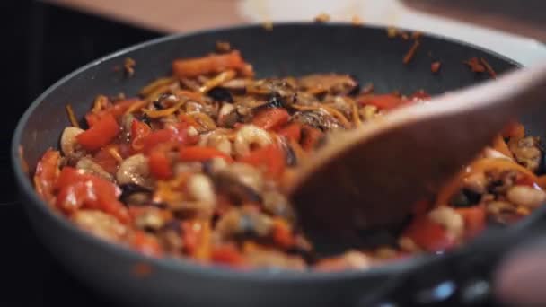 Las hembras mezclan a mano los ingredientes en una sartén con cuchara de madera. — Vídeos de Stock