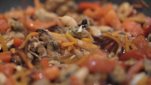 Соус наливают в сковородку с морепродуктами и овощами. — стоковое видео