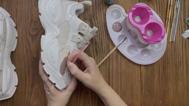 Girls hands drawing on white boots with brush on desktop. — Stock Video